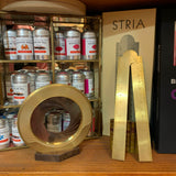 A Stria ruler and an Iris drawing compass on a shelf in front of some ink cartridges.